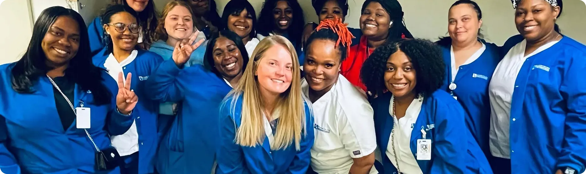 A group of smiling nursing students in scrubs gathered together