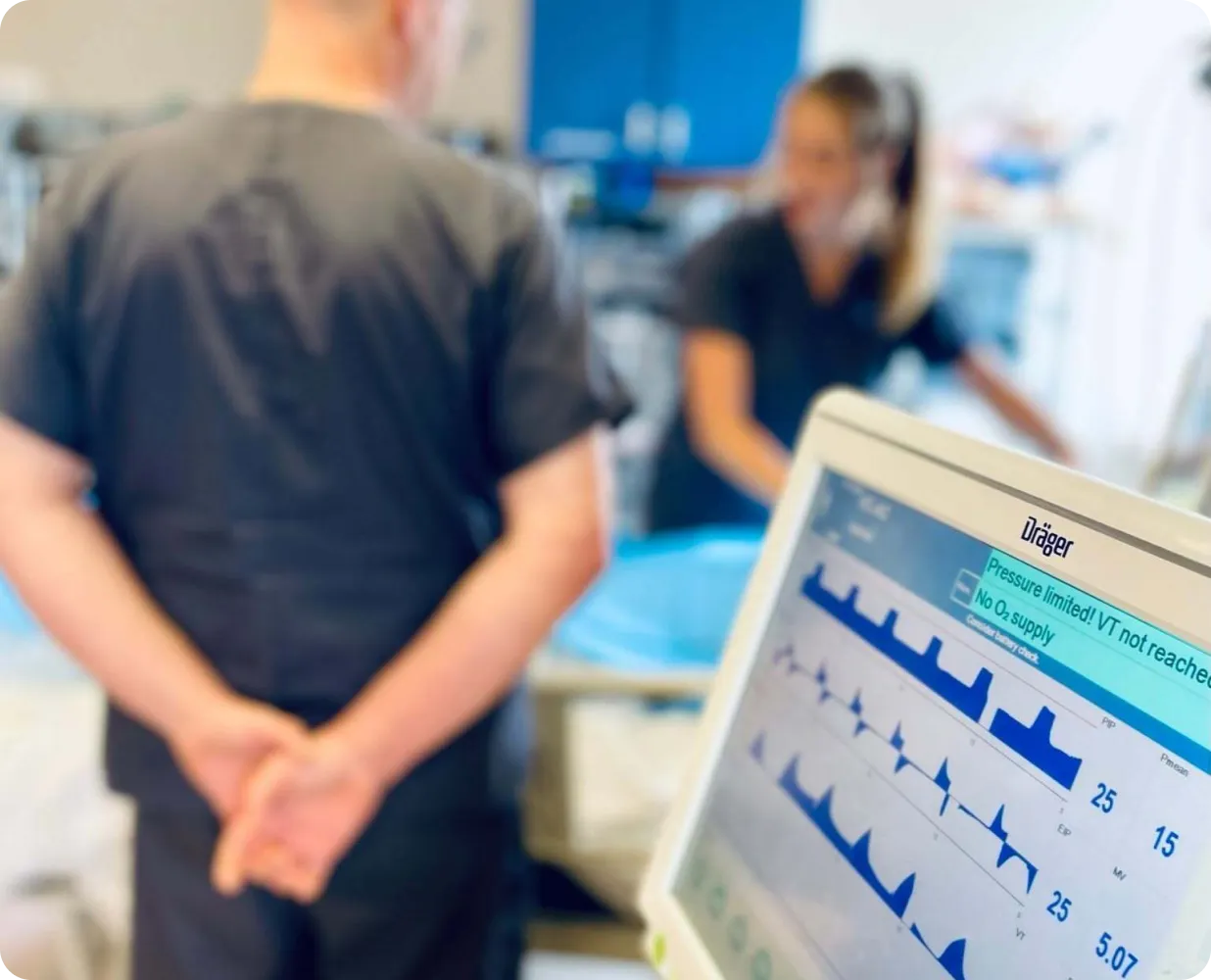 Respiratory therapists monitoring ventilator waveforms at a patient bedside