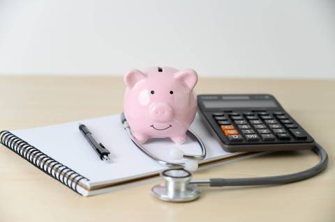 piggy bank on medical items and notebook piggy bank on a notebook with pen and stethoscope