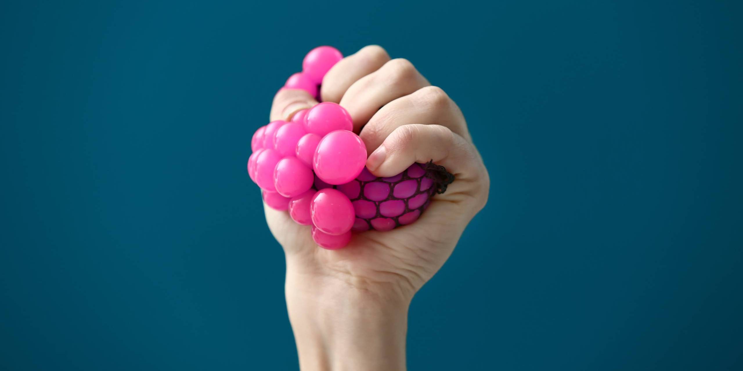 squeezing a pink stress relief ball-min stress relief tips for college students