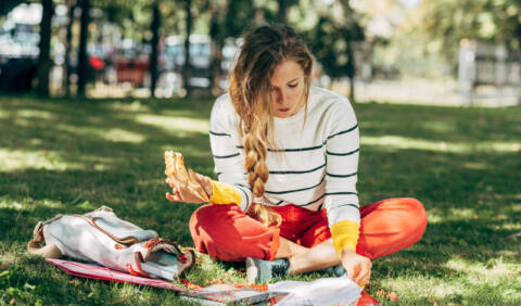 Horizontal outdoor student female sitting on the green grass the healthy college eating habits