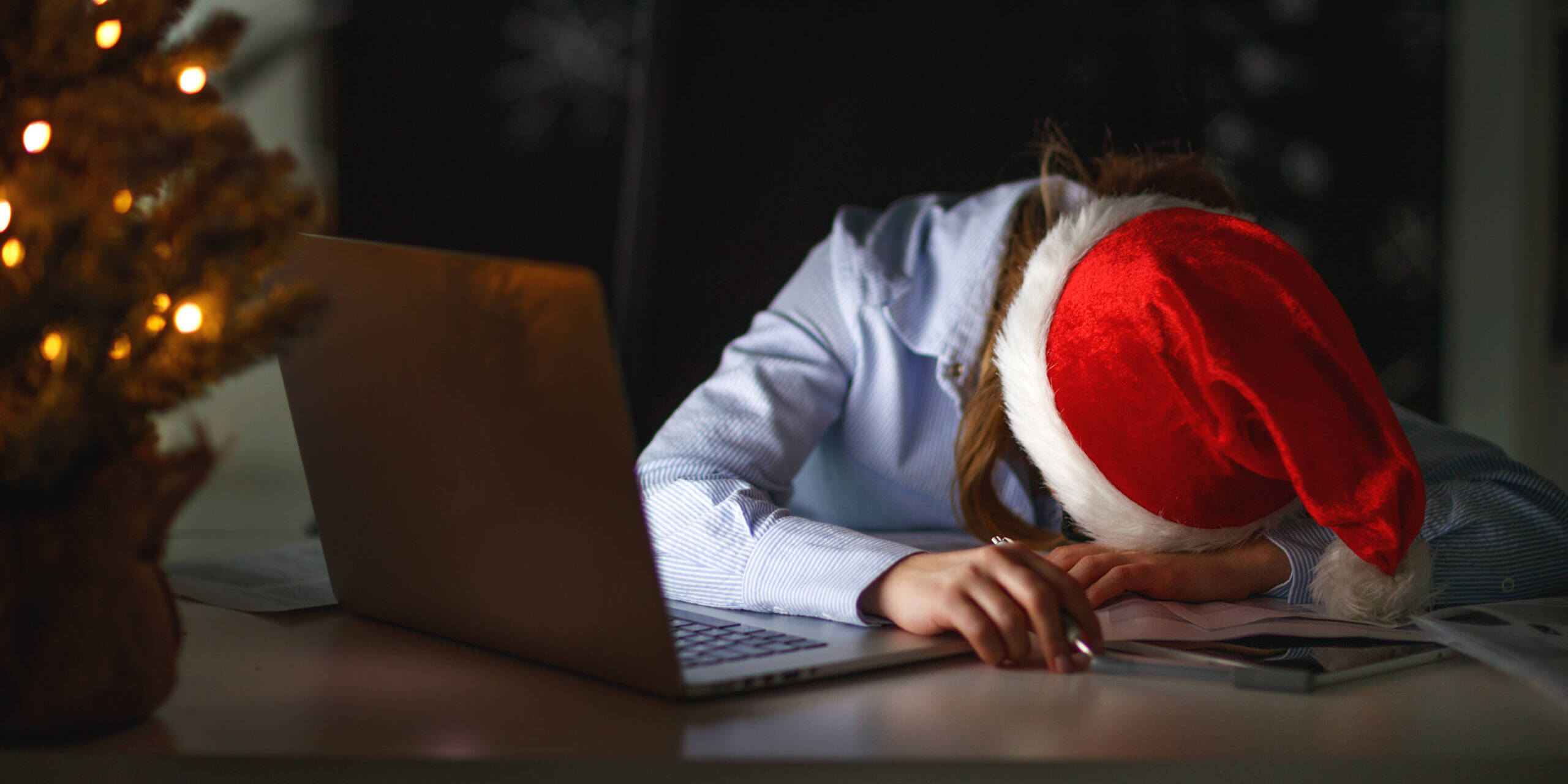 businesswoman freelancer tired, asleep working at computer at Christmas coping with holiday stress