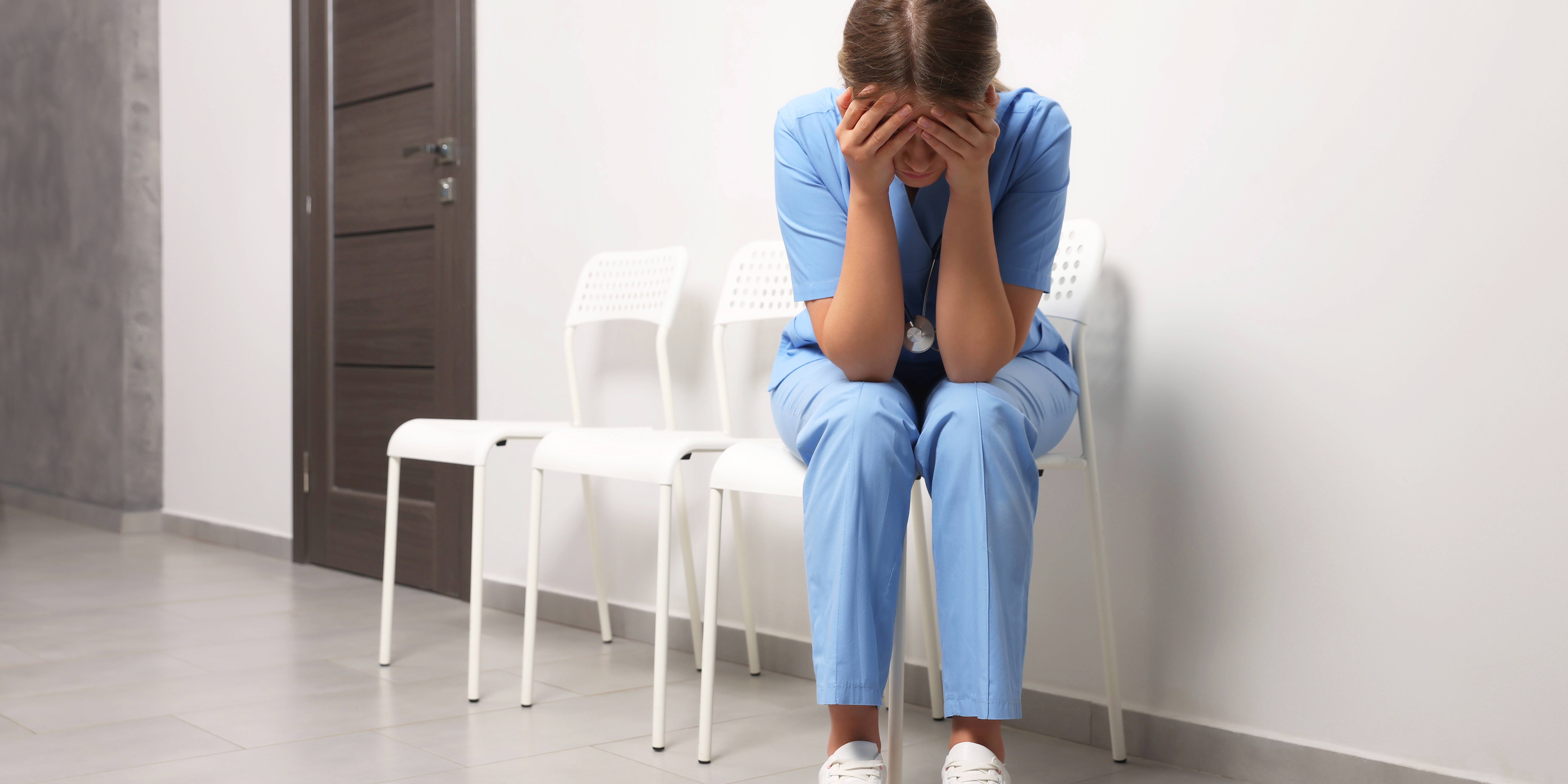 Exhausted doctor sitting on chair in hospital, space for text