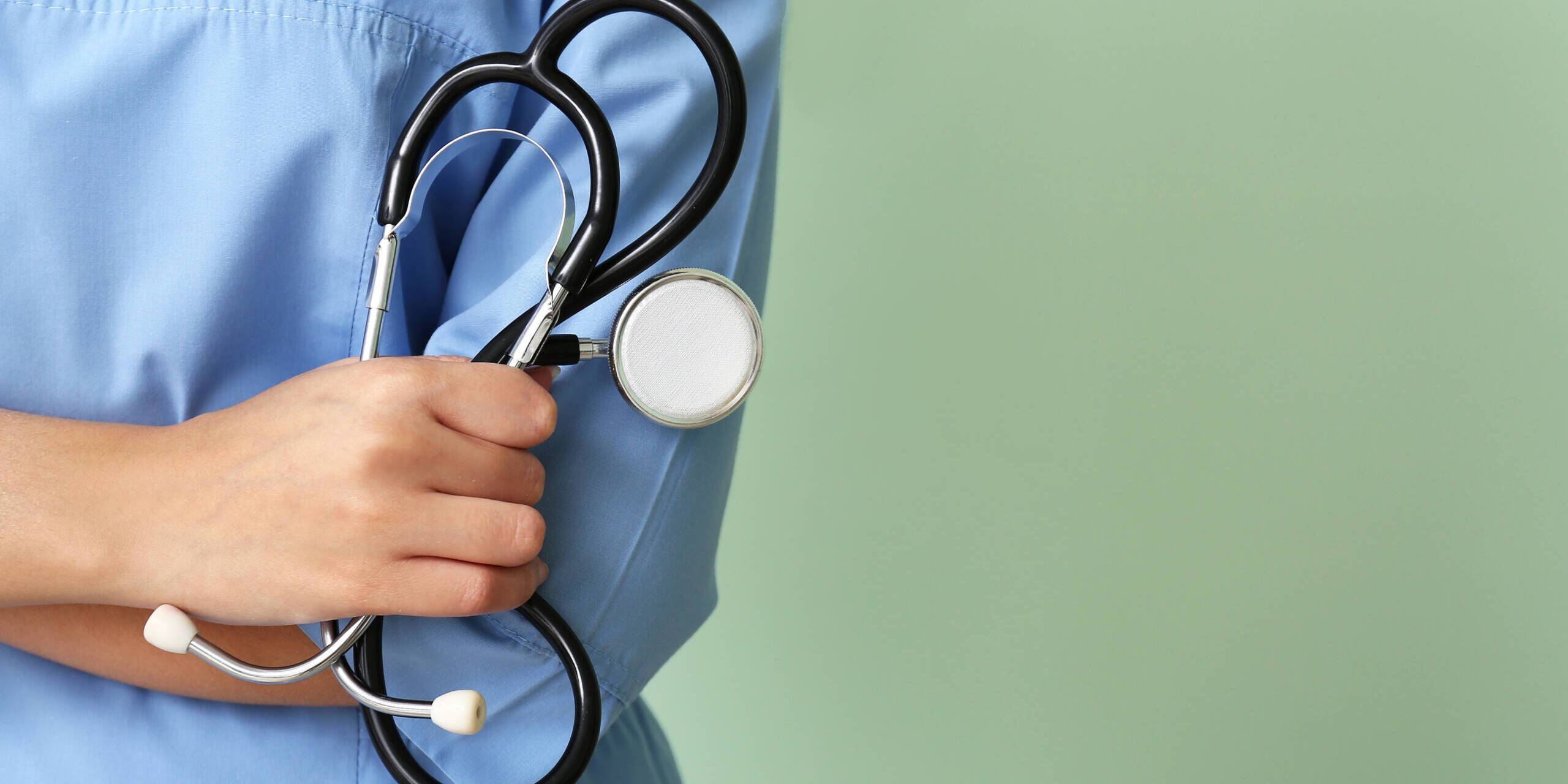 how to fix the nursing shortage Young nurse with stethoscope on color background, closeup