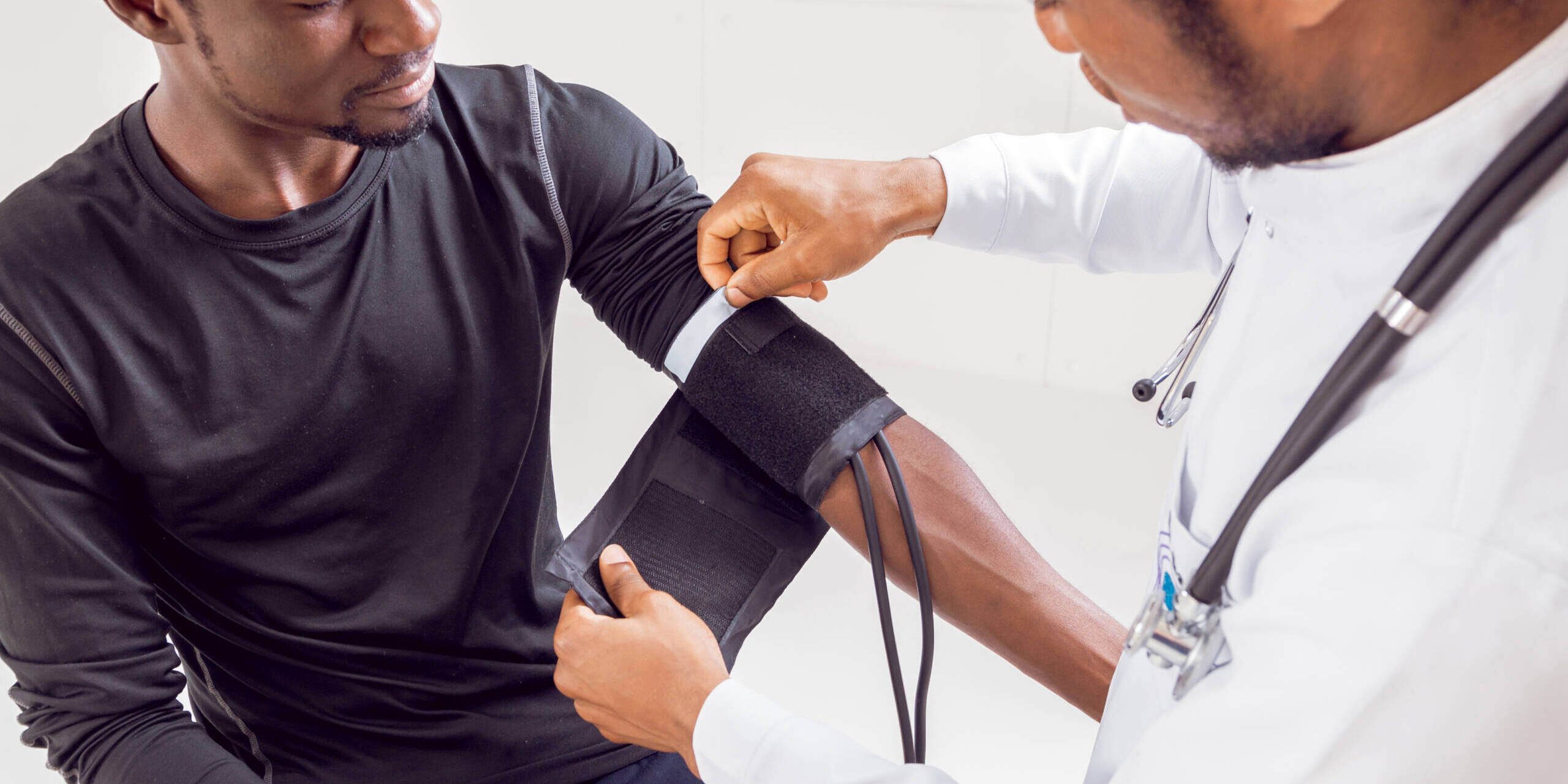 CNA vs PCT an african american doctor is taking a patient's blood pressure