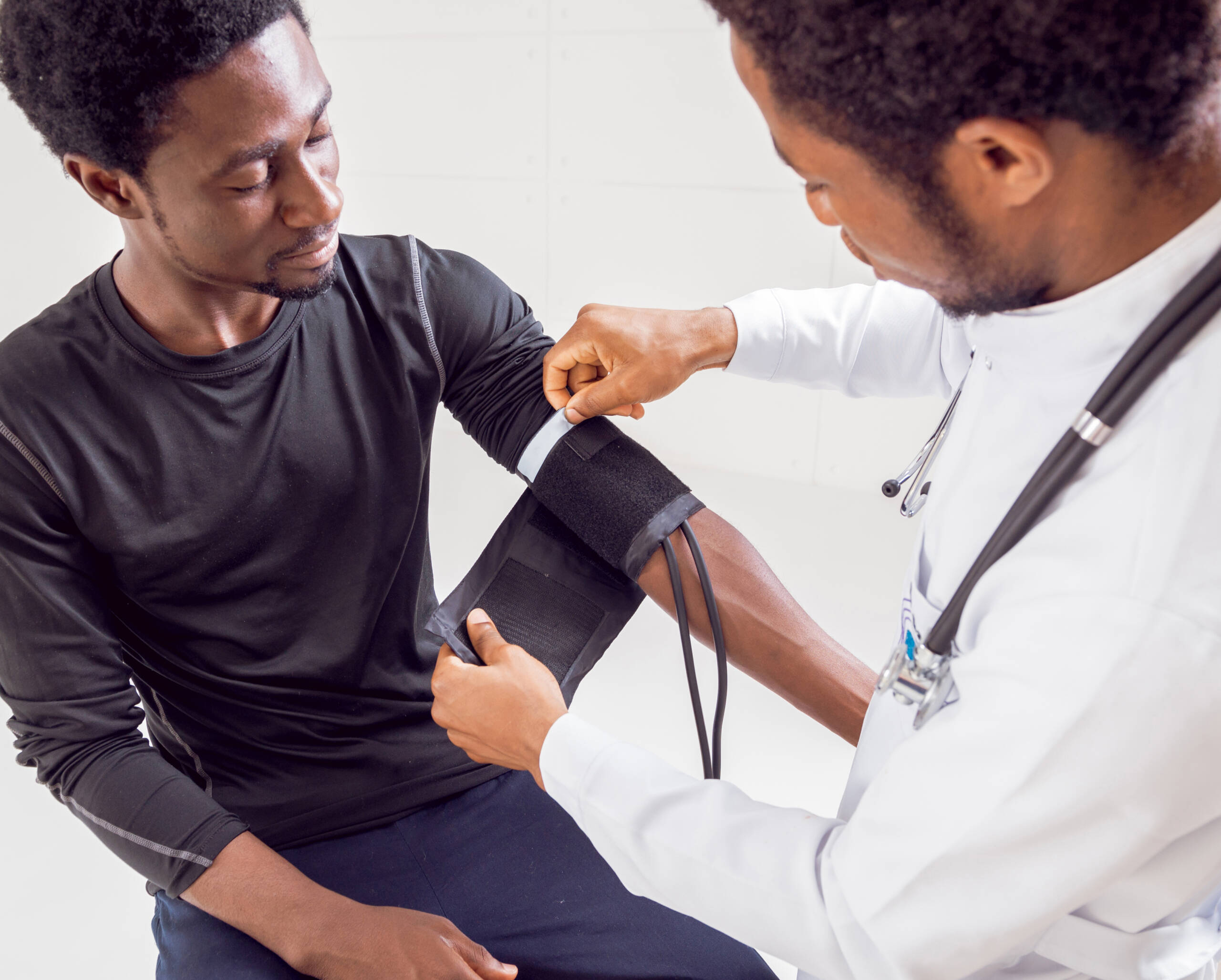 CNA vs PCT an african american doctor is taking a patient's blood pressure