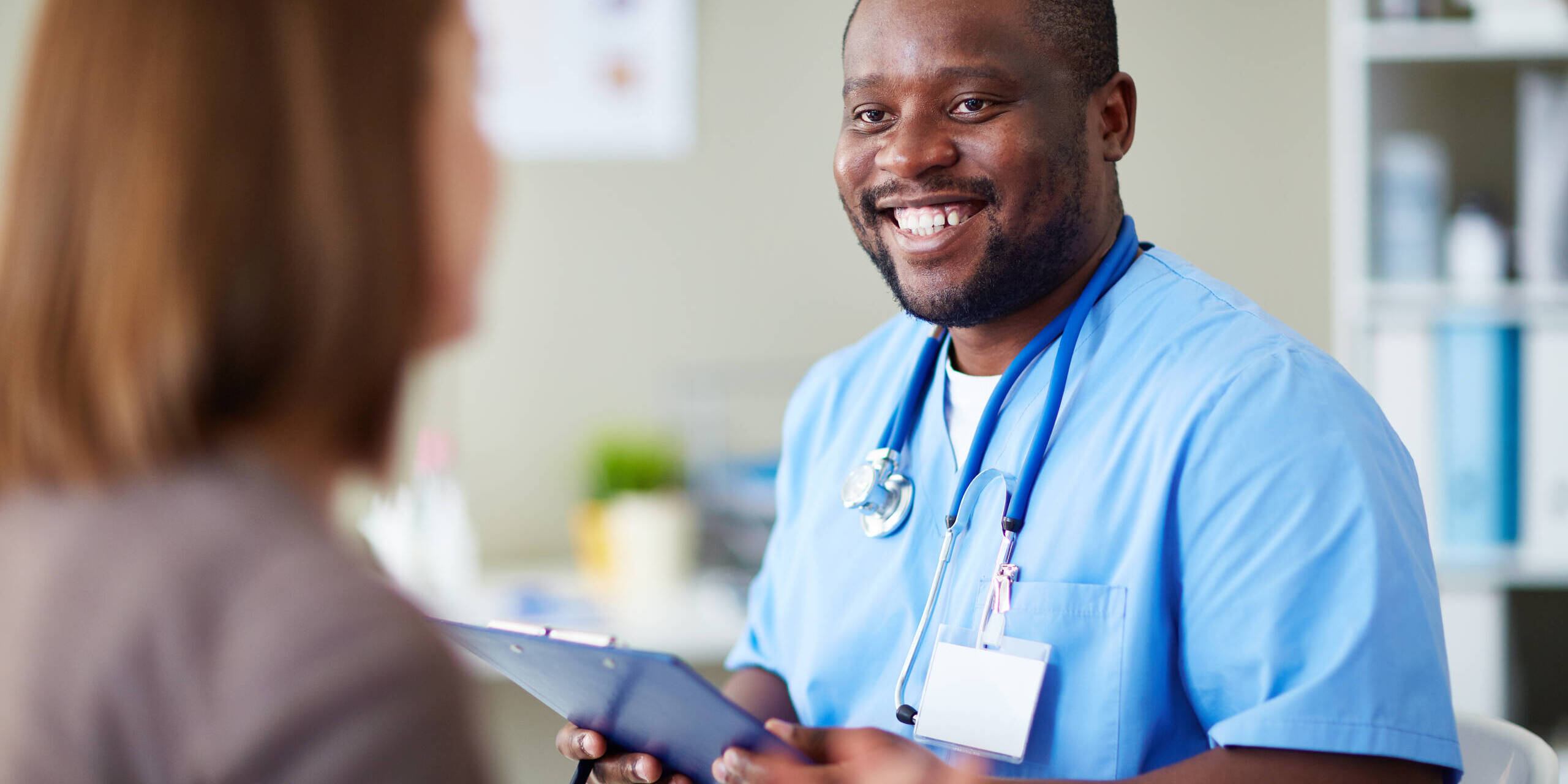 Smiling African doctor working with patient in his office