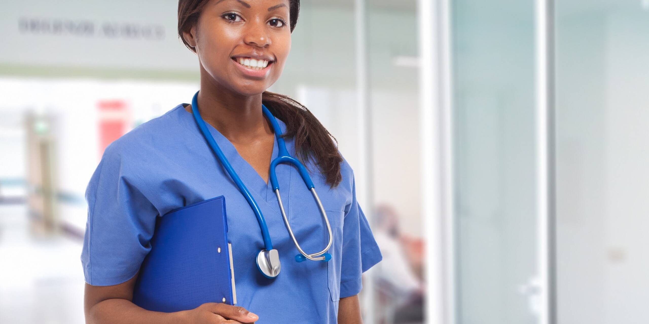 Traveling Nurse An african american female travel nurse is in the medical office and holding a clip board