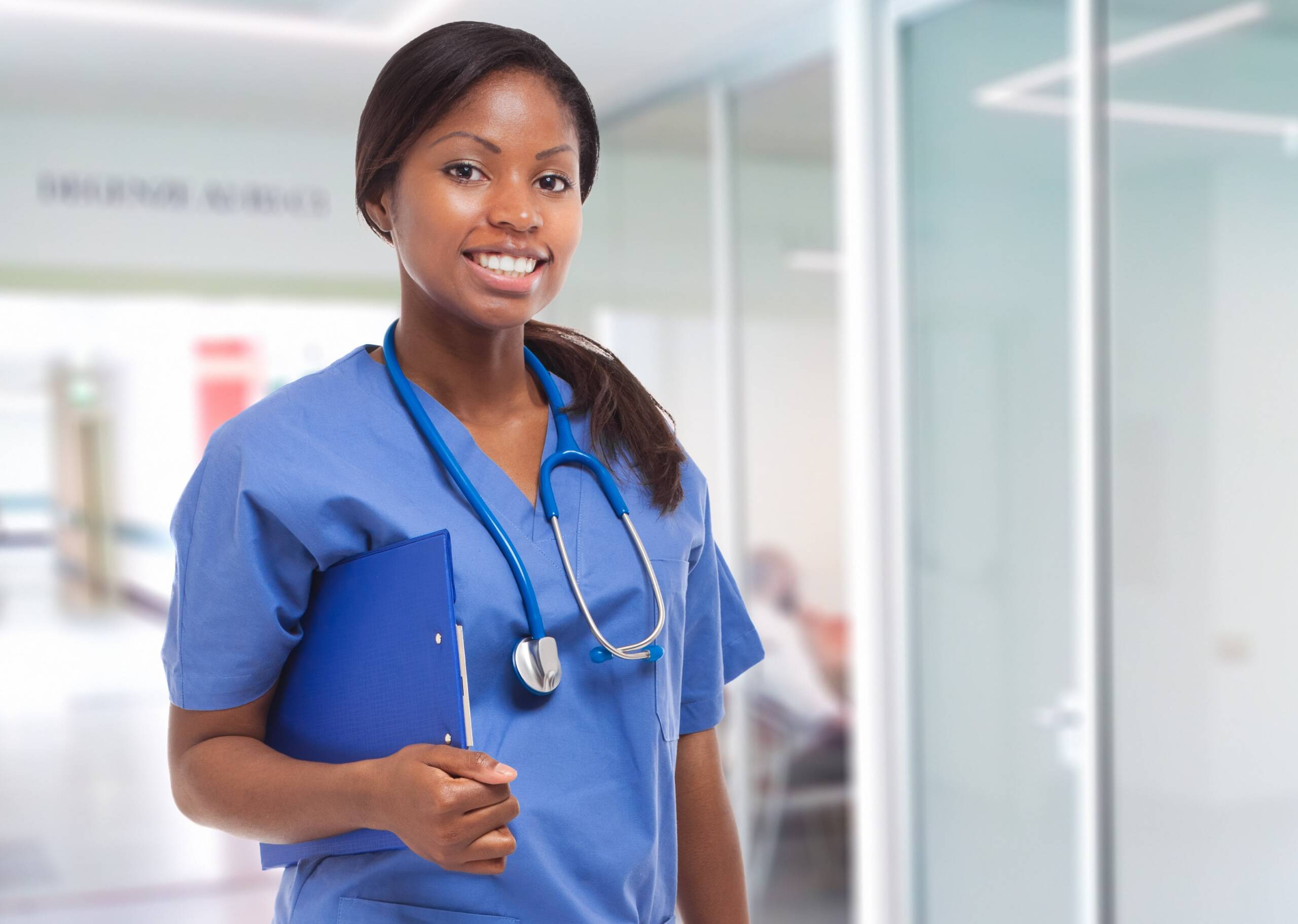 Traveling Nurse An african american female travel nurse is in the medical office and holding a clip board