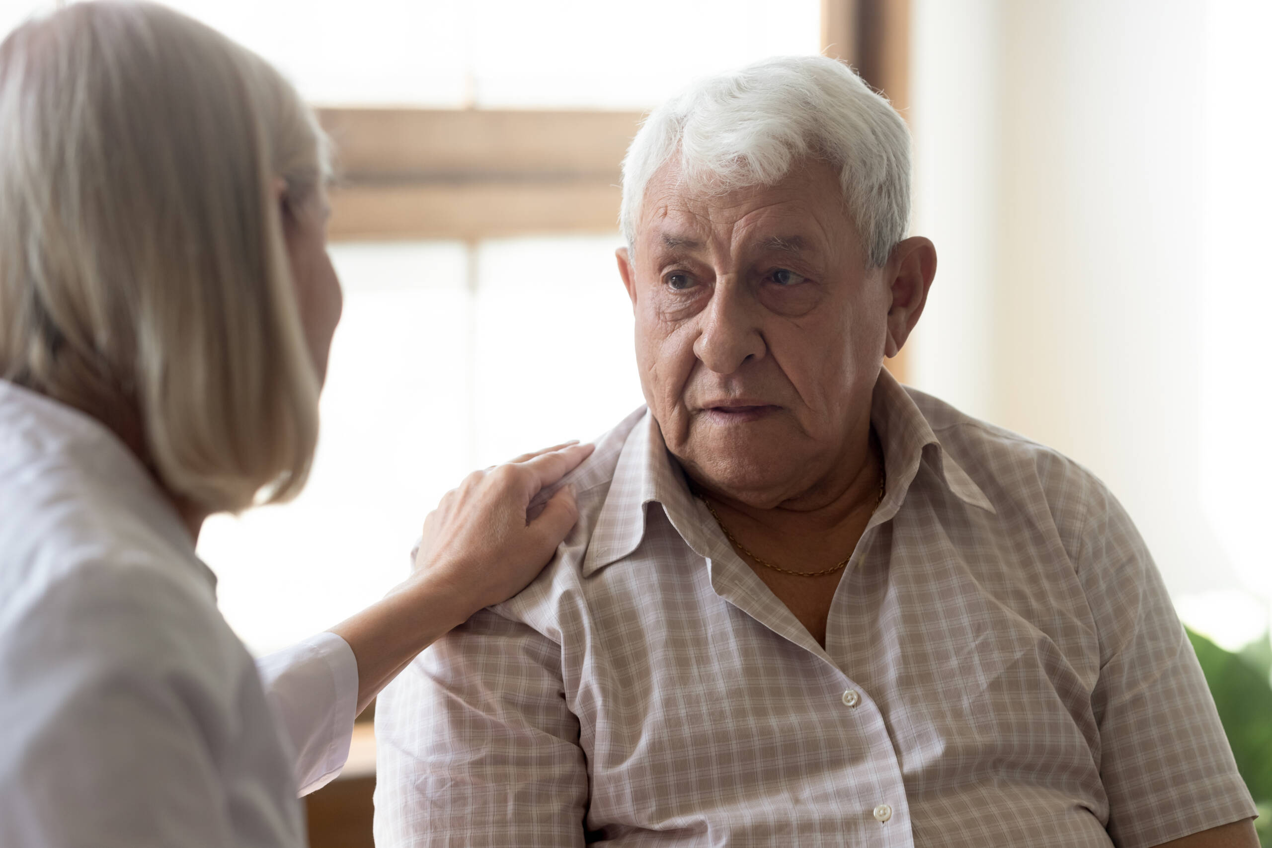 LPN Assisting Patient 70s man patient and licensed practical nurse communicating indoors