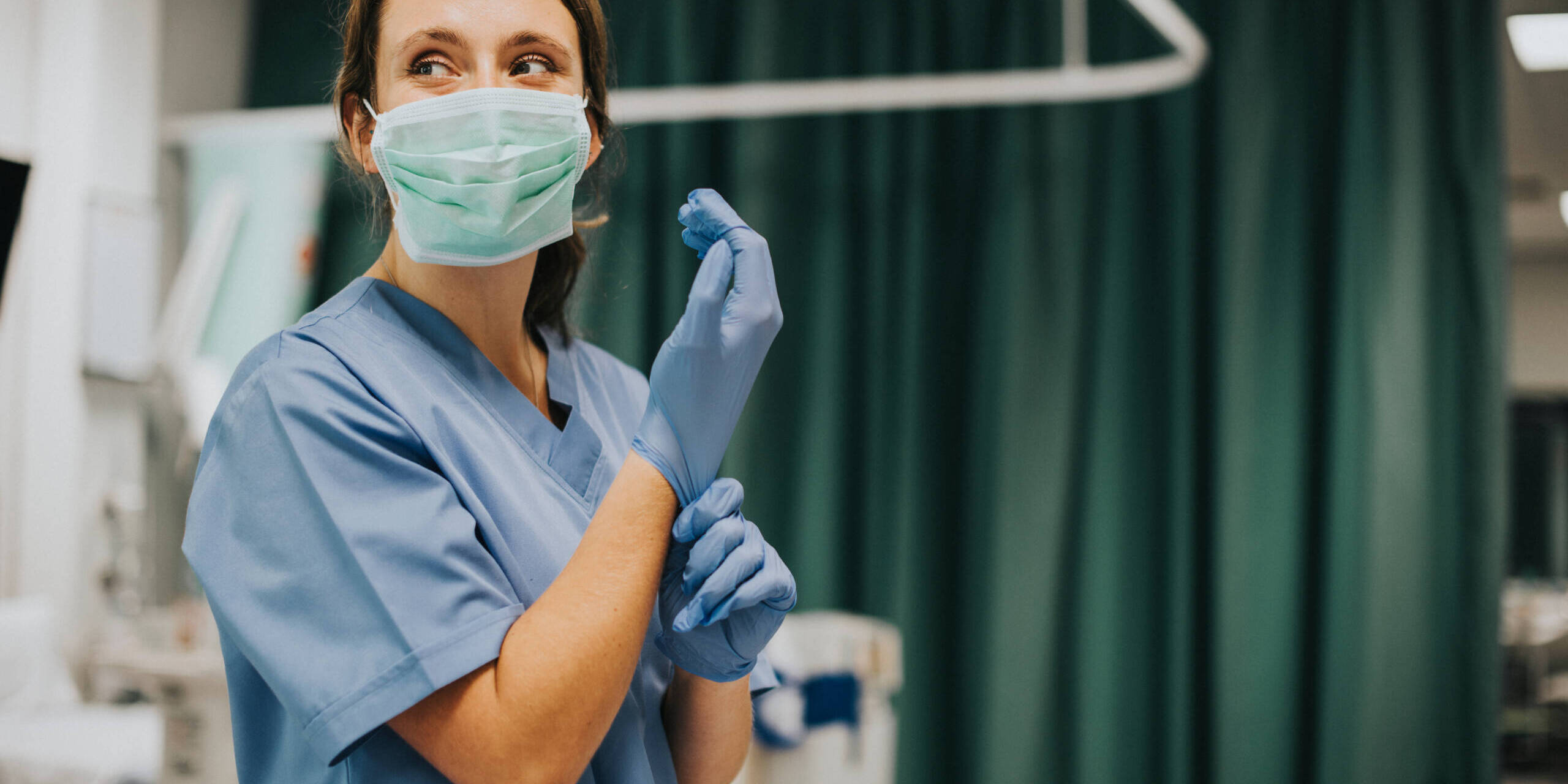 Female nurse with a mask putting on gloves