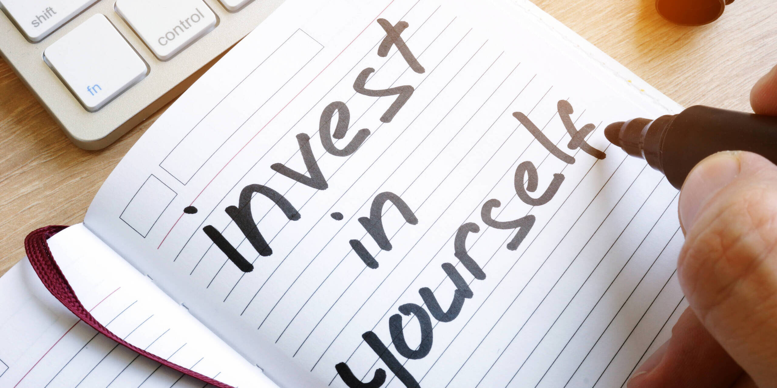 Man is writing invest in yourself in a note. professional development